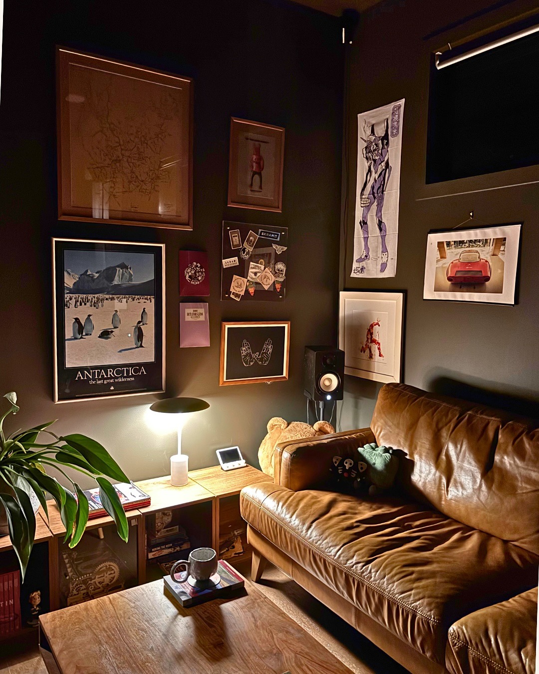A considered interior: layered gallery wall, leather sofa, warm lamp light